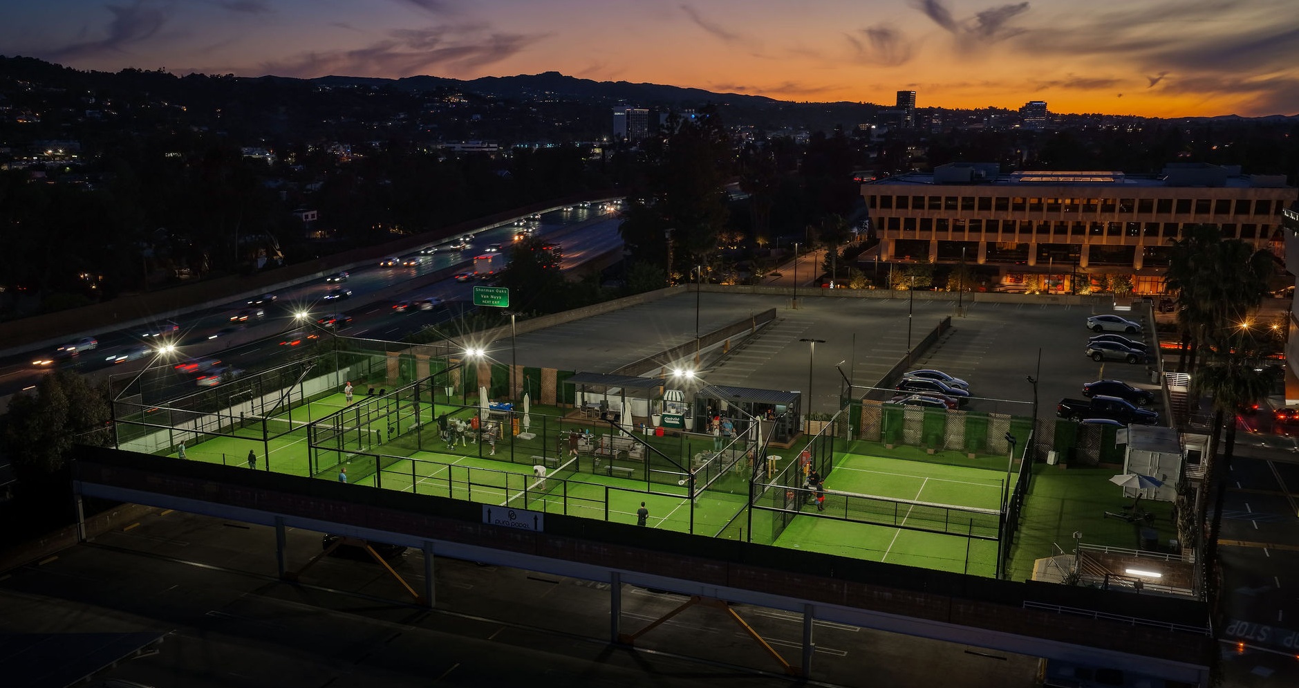 Aerial drone view of the Pura Padel rooftop courts at sunset above Westfield Fashion Square in Sherman Oaks, Los Angeles